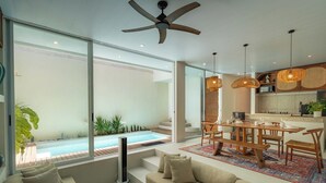 Un salon moderne avec piscine, coin repas et cuisine.