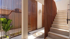Un escalier moderne avec une rampe en bois, une plante en pot et un tapis décoratif.