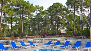 A pool area with blue lounge chairs and a tiled pool. - Les Grands Pins by Interhome (Maubuisson)