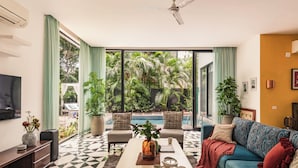 A living room with a pool view, a sofa, a coffee table, and a TV. - TBK VILLA VAGATOR 15 (Vagator)