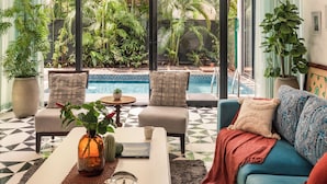 A modern living room with a pool view, a coffee table with tea set, and a blue sofa. - TBK VILLA VAGATOR 15 (Vagator)