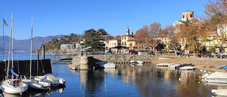 A marina with boats docked, a stone pier, and buildings with a church tower in the background.