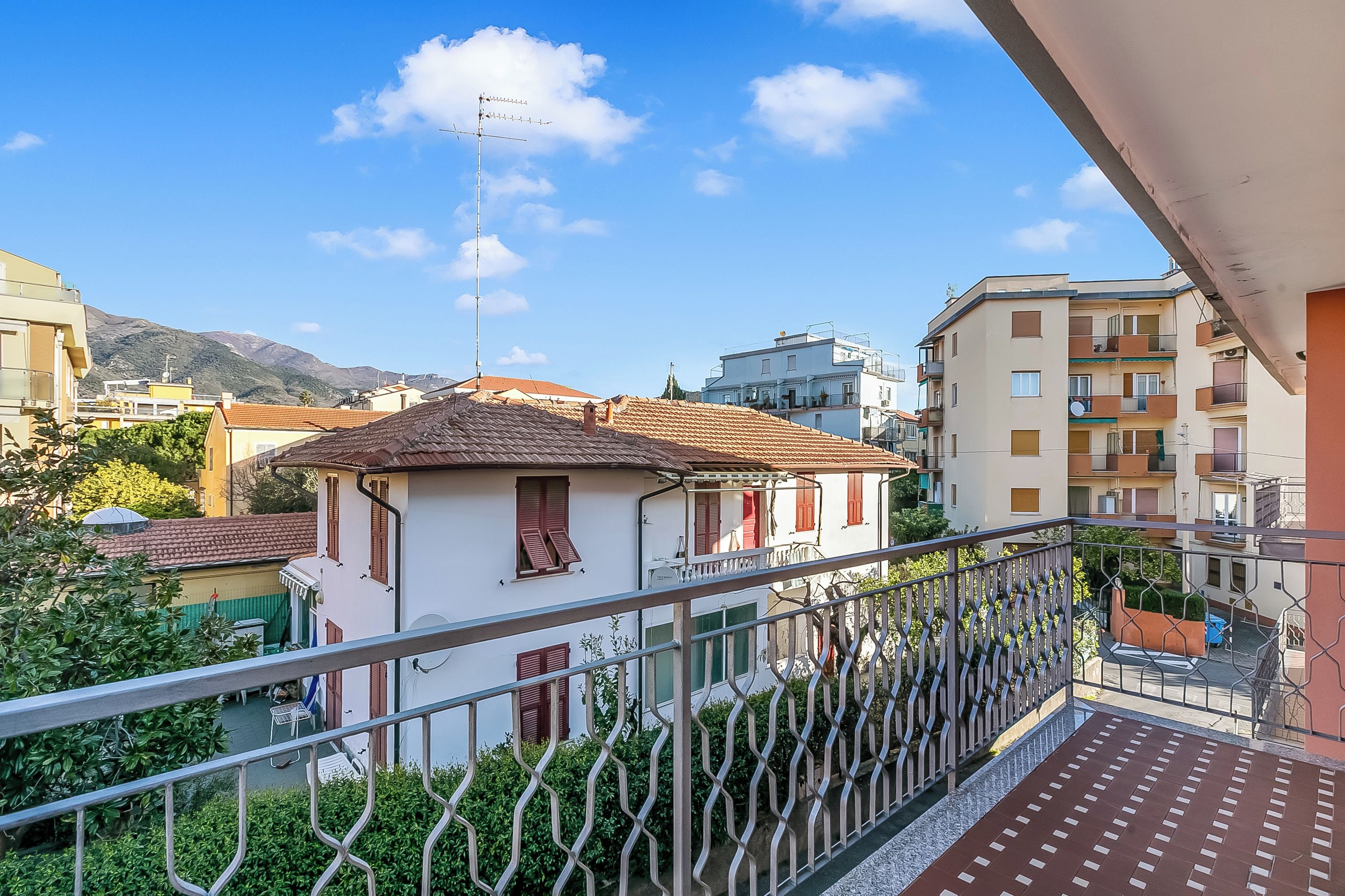 A residential balcony with a metal railing, a small table, and a chair.