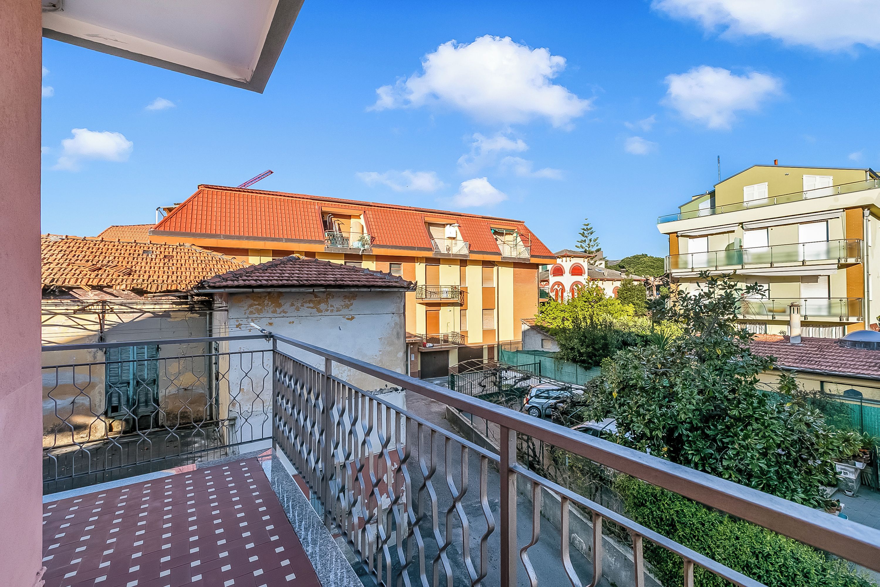A balcony with a metal railing, a tiled roof, and a clear blue sky.