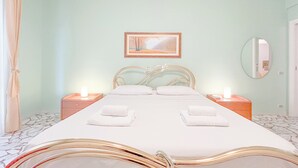 Een netjes ingerichte slaapkamer met een bed, nachtkastjes, een spiegel en een ingelijst kunstwerk aan de muur.