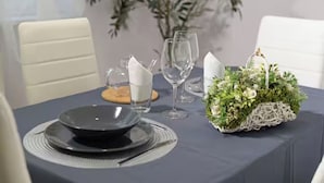 Una tavola imbandita con piatti, bicchieri e un centrotavola.