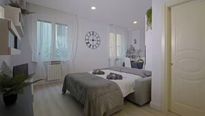 Una camera da letto moderna con un letto, comodini, una sveglia e una pianta in vaso.