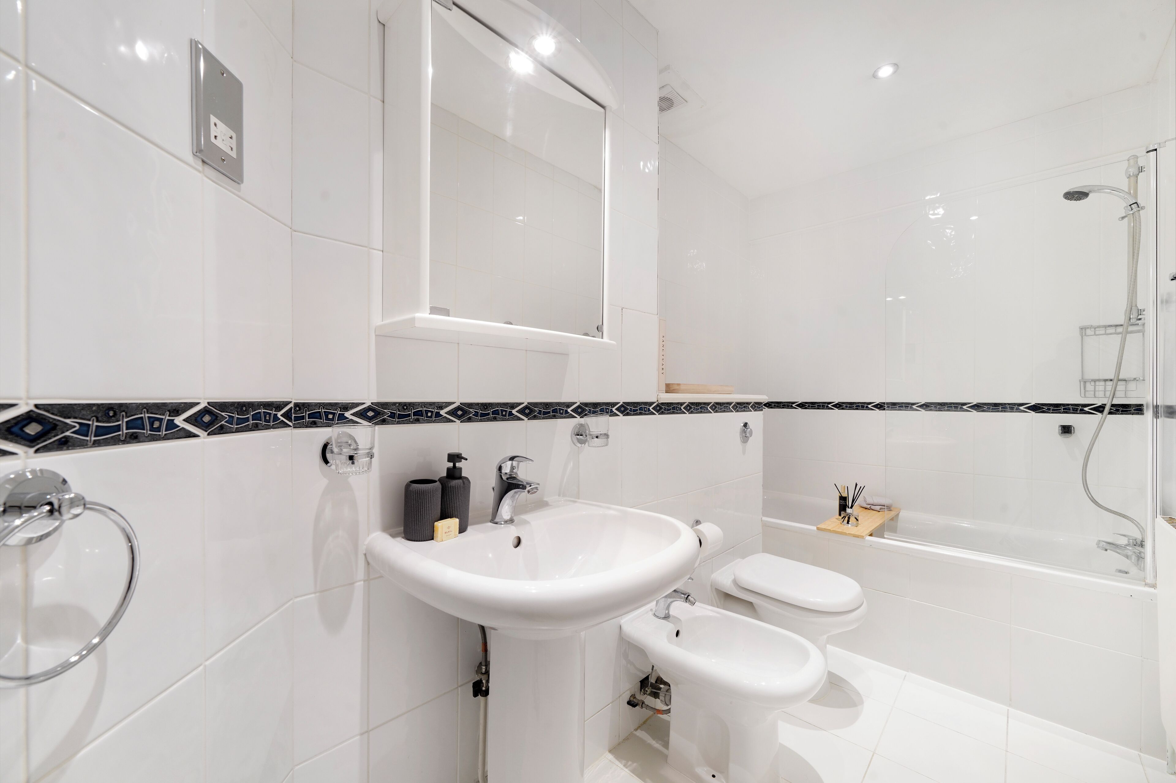 A modern bathroom with a white sink, toilet, and bathtub.