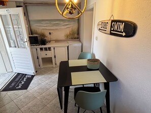Ein Essbereich mit Tisch, Stühlen, einem an der Wand befestigten Schild und einer Küche im Hintergrund.