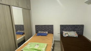 Un dormitorio con dos camas, un armario y una lámpara en el techo.