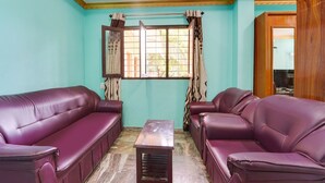 A room with two purple leather sofas, a wooden coffee table, and a window with patterned curtains. - Super Hotel O Kanyakumari Near Sunrise View (Nagercoil)