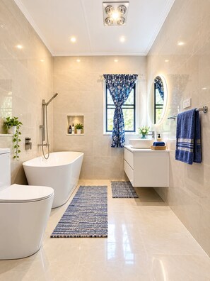Une salle de bain moderne avec une baignoire sur pieds, des toilettes, un lavabo et une douche.