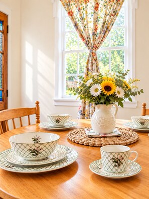 Une table à manger dressée avec de la vaisselle à motifs et un vase rempli de tournesols.