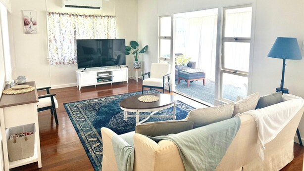 A living room with a flat-screen TV, a sofa, a coffee table, and a potted plant. - Cosy spacious Holiday Family Home within minutes walking distance to waterfront (Margate)