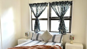 A bedroom with a bed, two nightstands, a ceiling fan, and a window with curtains. - Cosy spacious Holiday Family Home within minutes walking distance to waterfront (Margate)