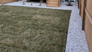 A two-story residential building with a wooden deck and a small garden area. - Starling Heaven (Fort Saskatchewan)