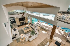 Un vaste espace de vie doté d’une cheminée, de coins salon et offrant une vue sur la piscine.
