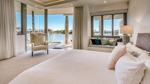 A spacious bedroom with a large bed, a chaise lounge, a sofa with cushions, and a view of the sea. - Luxury Ghost Estate on the Noosa Sound (Noosaville)