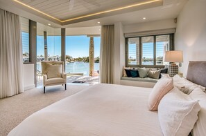Une chambre spacieuse avec un grand lit, une chaise longue, un canapé avec des coussins et une vue sur la mer.