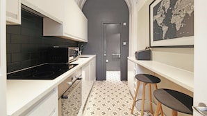 Une cuisine moderne avec des meubles blancs, une cuisinière noire et un sol carrelé.