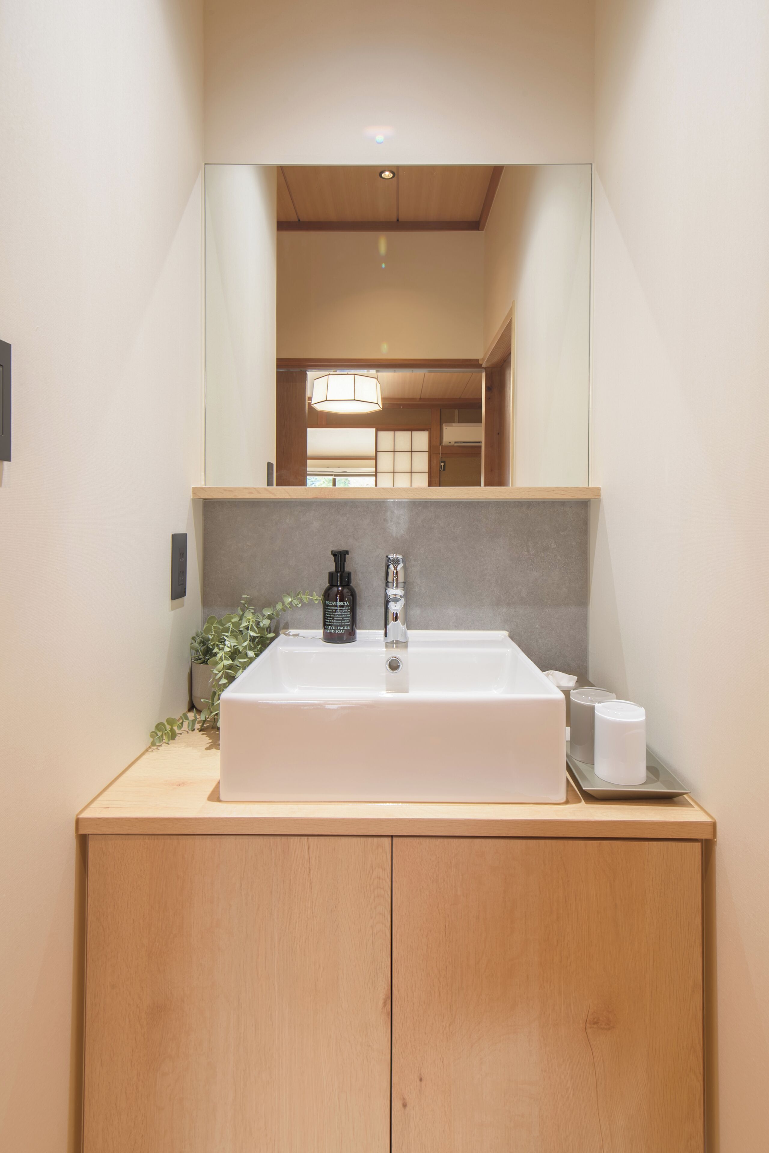 A bathroom with a large mirror, a sink, and a wooden cabinet.