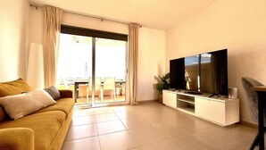 A living room with a sofa, a flat-screen TV on a stand, and a sliding glass door leading to an outdoor area. - Welooveyou Baltico your place to discover the island (Costa Calma (incl. Urbanización Cañada del Río))