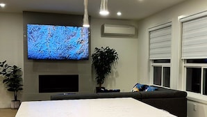 Una cocina moderna con una isla grande, luces colgantes, un televisor de pantalla plana y una planta en maceta.