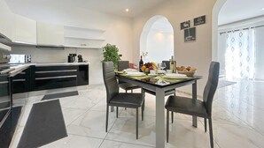 Una cocina moderna con zona de comedor, que incluye una mesa para cuatro, una cafetera y una planta.