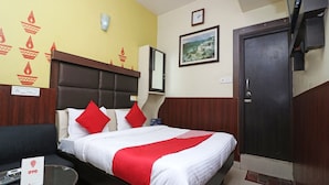 A hotel room with a bed, a sofa, a desk, and a door.