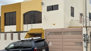 Een modern gebouw met een beige gevel en een grote garagedeur, met een Mitsubishi SUV ervoor geparkeerd.
