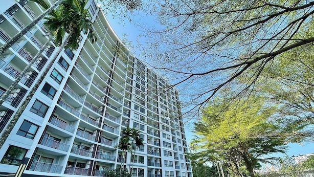 Um hotel com várias andares e varandas, rodeado por árvores e céu claro.