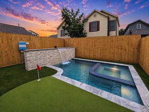 A backyard with a swimming pool, a wooden fence, and a house in the background. - Downtown Retreat | Covered Rooftop w/Skyline Views (Houston)