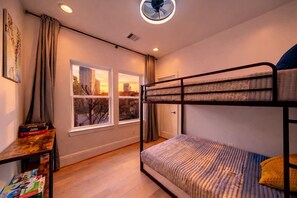 Habitación con literas, vista a la ciudad, una mesa con libros y un ventilador de techo.