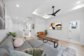 Una sala de estar moderna con un sofá modular, una mesa de centro y un ventilador de techo.