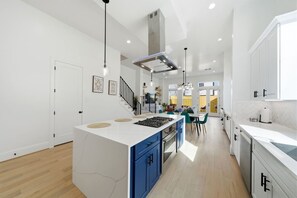 Uma cozinha moderna com uma ilha central, armários azuis e uma escada que leva a um andar superior.