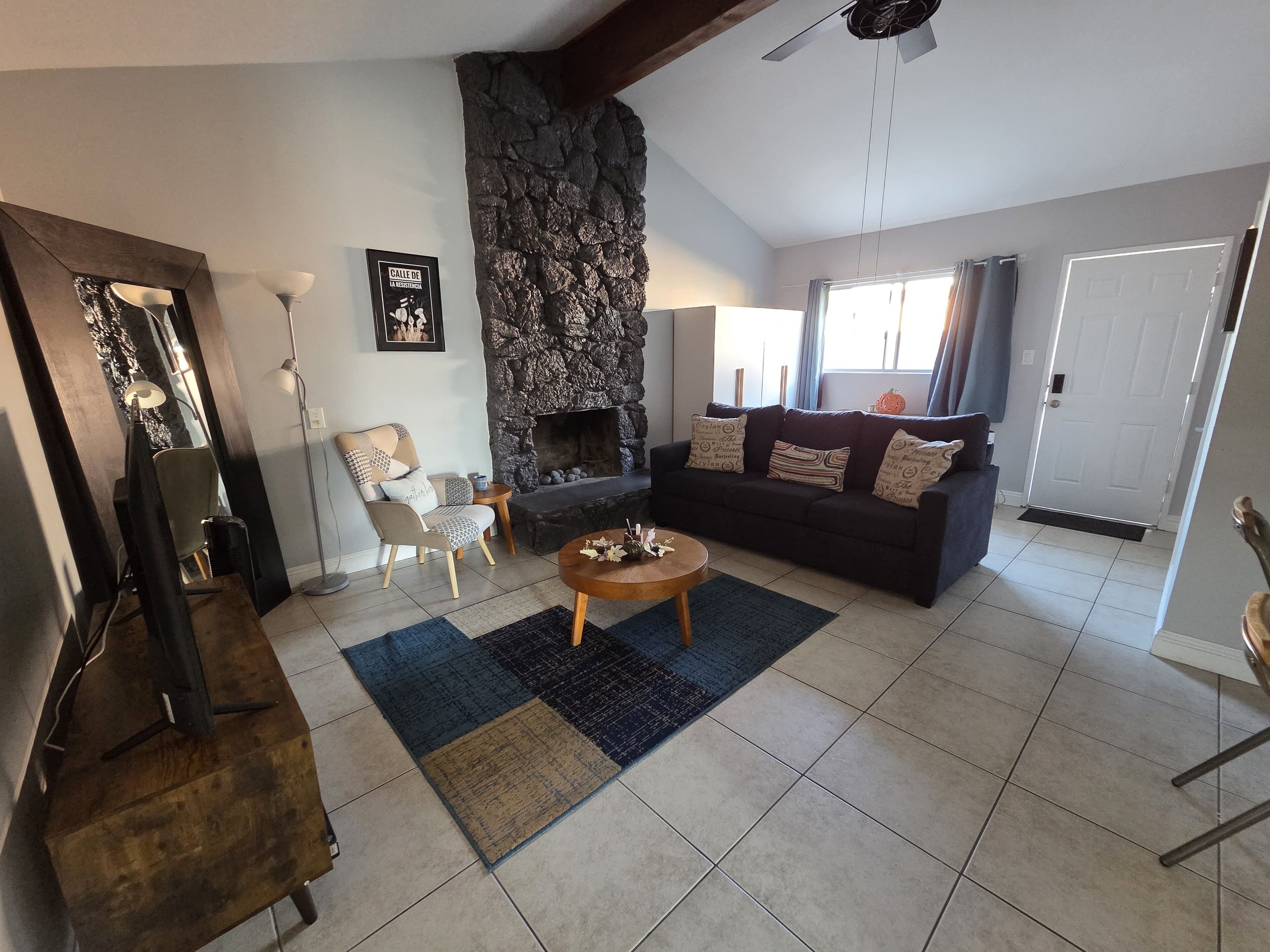 A living room with a stone fireplace, a sofa, a coffee table, and a chair.
