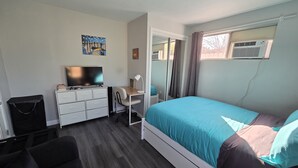 Une chambre à coucher avec un lit, un bureau, une télévision et une commode.