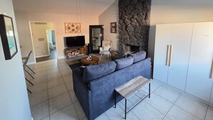 Una sala de estar moderna con chimenea de piedra, un televisor grande y un sofá gris.