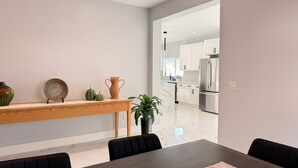 Een moderne eetruimte met een houten tafel, zwarte stoelen en een decoratieve vaas.