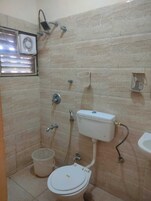 A small bathroom with a toilet, bidet, and a window with blinds.