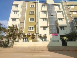 A multi-story building with a central staircase, air conditioning units, and a gated entrance.