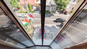 Une vue depuis une fenêtre donnant sur la rue, avec une perspective dégagée sur les voitures garées et les bâtiments.