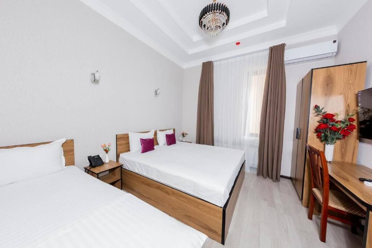 Habitación de hotel con dos camas, un escritorio de madera, televisión y candelabro.