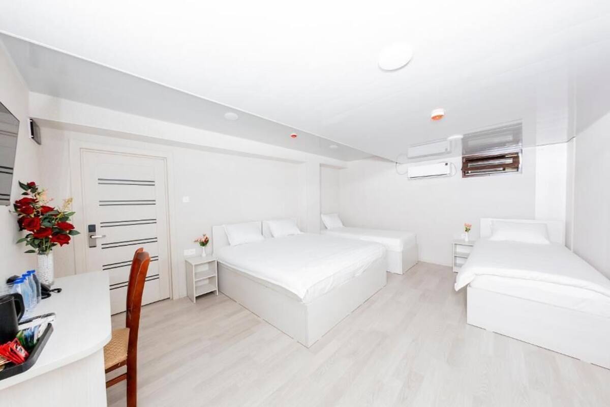 Un dormitorio moderno con decoración en blanco, una cama grande, mesitas de noche y una pequeña zona de escritorio.