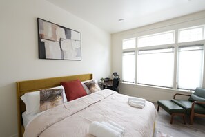 A neatly arranged bedroom with a bed, pillows, a desk, and a chair. - Spacious & Luxury Seattle Oasis: Sauna, Hot Tub & Capitol Hill Proximity (Seattle)