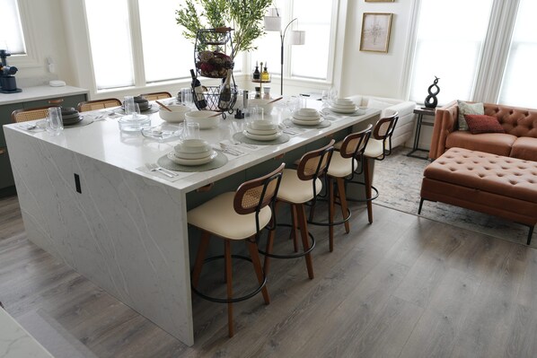 A modern kitchen with a large island, wooden chairs, and a brown leather sofa. - Spacious & Luxury Seattle Oasis: Sauna, Hot Tub & Capitol Hill Proximity (Seattle)