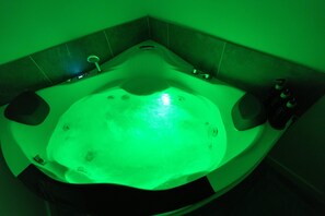 A green-lit hot tub in a corner of a room with tiled walls and a small window. - Spacious & Luxury Seattle Oasis: Sauna, Hot Tub & Capitol Hill Proximity (Seattle)