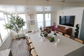 A modern living room with a large white marble table, a brown leather sofa, and a television mounted on the wall. - Spacious & Luxury Seattle Oasis: Sauna, Hot Tub & Capitol Hill Proximity (Seattle)