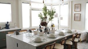 Ett modernt kök med en stor köksö, vita skåp och en sittgrupp med en soffa och stolar.