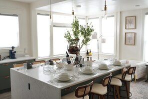 A modern kitchen with a large island, white cabinetry, and a seating area with a sofa and chairs. - Spacious & Luxury Seattle Oasis: Sauna, Hot Tub & Capitol Hill Proximity (Seattle)